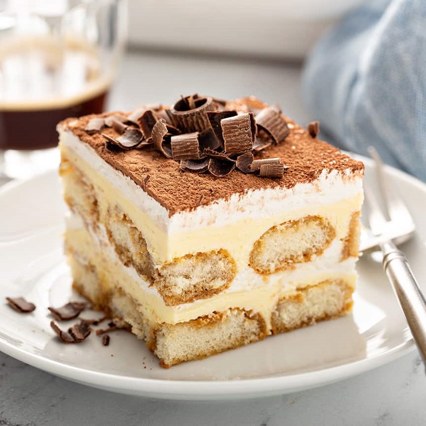 Close up shot of a slice of tiramisu topped with shaved chocolate served with an espresso