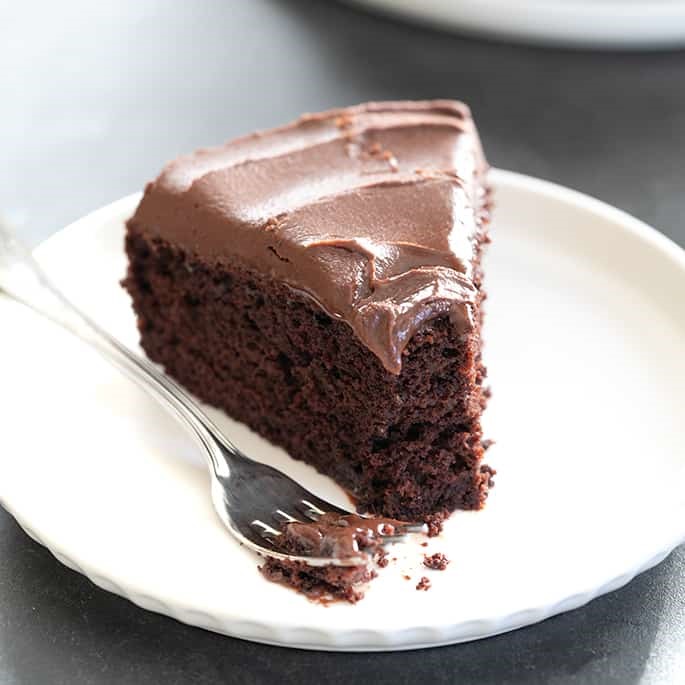 Clsoe up shot of a slice of chocolate cake topped with ganache